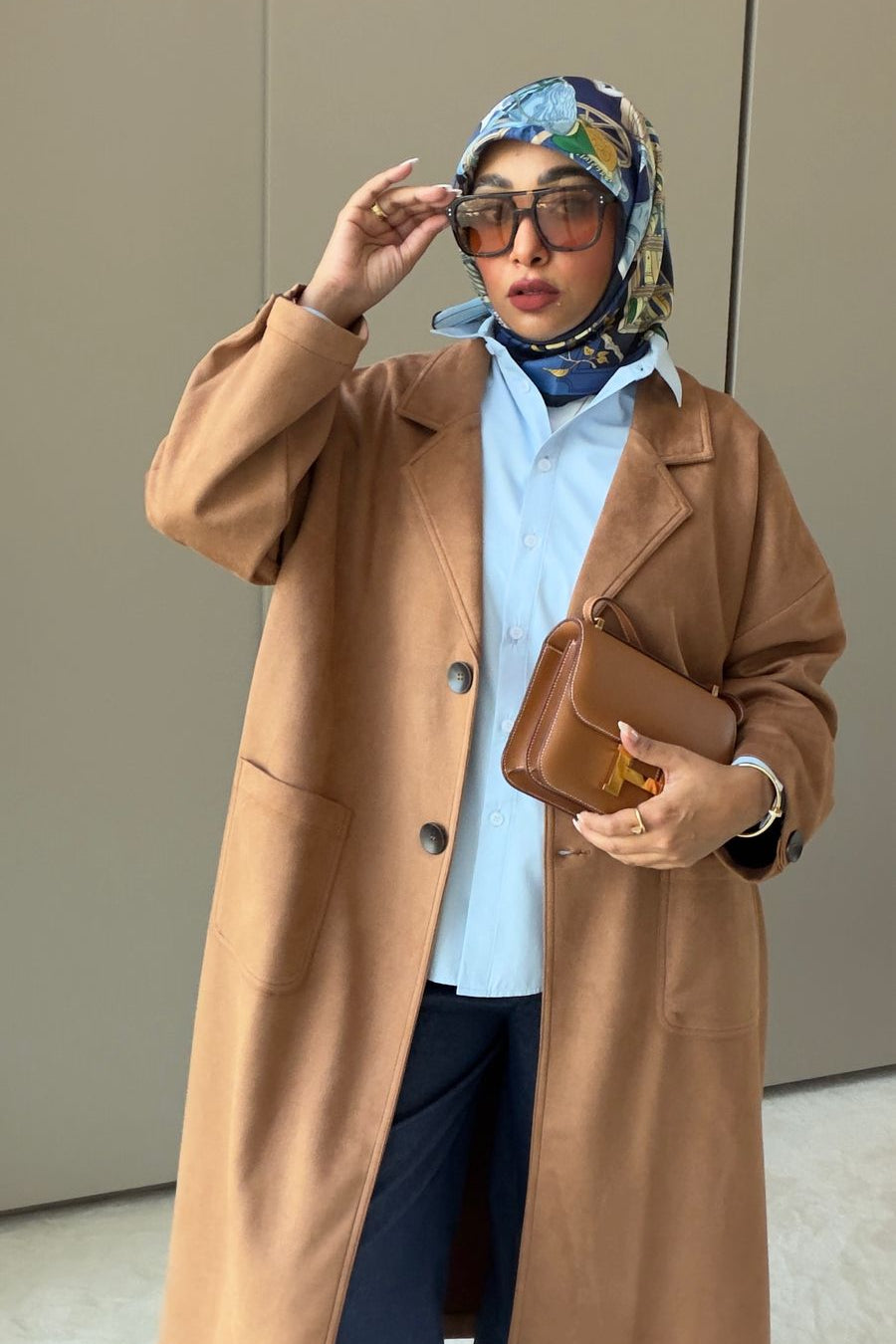 Person wearing a brown coat and colorful headscarf indoors