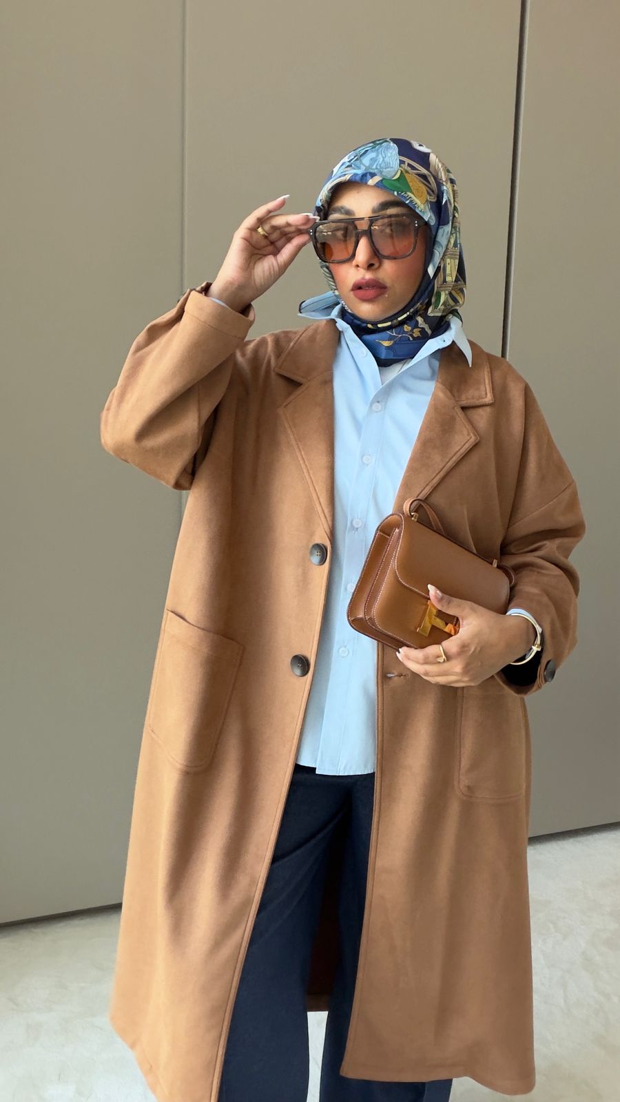 Person wearing a brown coat and colorful headscarf indoors